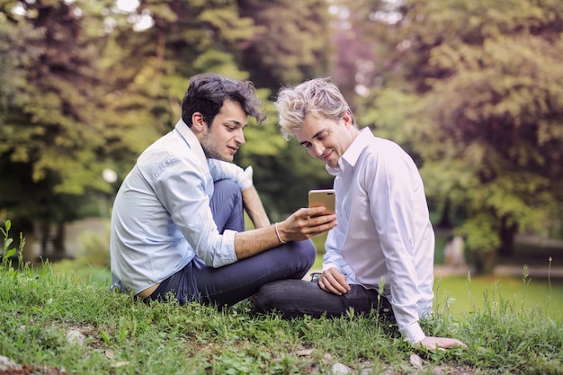 Couple gay vérifiant un smartphone dans le parc