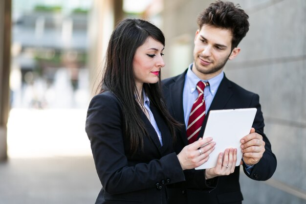 Couple de gens d'affaires à l'aide d'une tablette en plein air