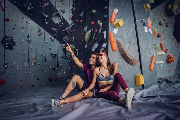 Un couple de grimpeurs contre un mur artificiel avec des poignées et des cordes colorées