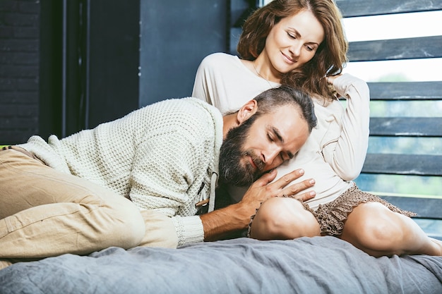 Couple hétérosexuel beau jeune homme et une femme enceinte sur le lit dans la chambre à la maison