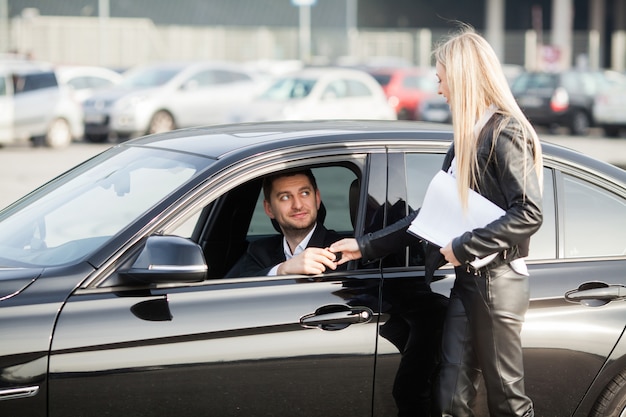 Couple heureux acheter une nouvelle voiture noire moderne