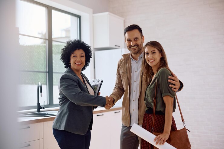 Photo un couple heureux et un agent immobilier se serrent la main et regardent la caméra.