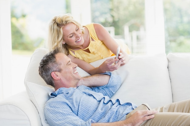 Couple heureux à l&#39;aide de smartphone dans le salon