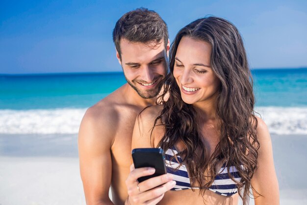 Couple heureux à l&#39;aide de smartphone à la plage