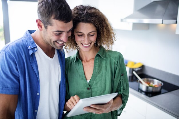 Couple heureux à l'aide de tablette numérique dans la cuisine