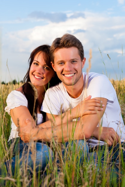 Couple heureux assis sur un pré s'embrasser