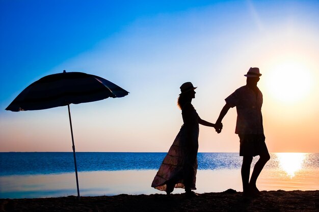 Un couple heureux au bord de la mer au coucher du soleil sur la silhouette de voyage dans la nature