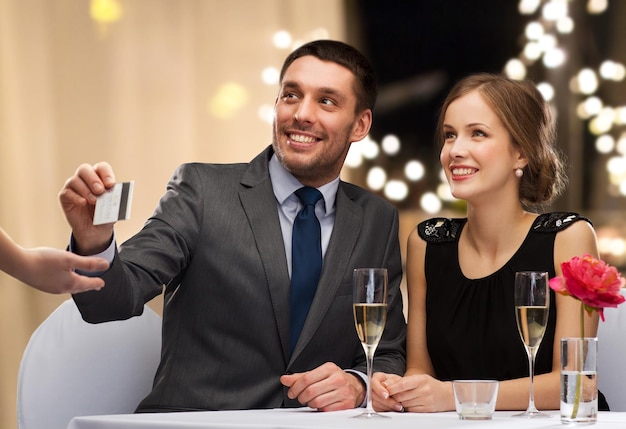 un couple heureux au restaurant payant par carte de crédit