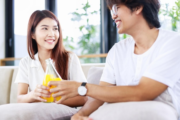 Un couple heureux boit du jus d'orange sur un canapé confortable à la maison Activités de loisirs pour les personnes - Mode de vie