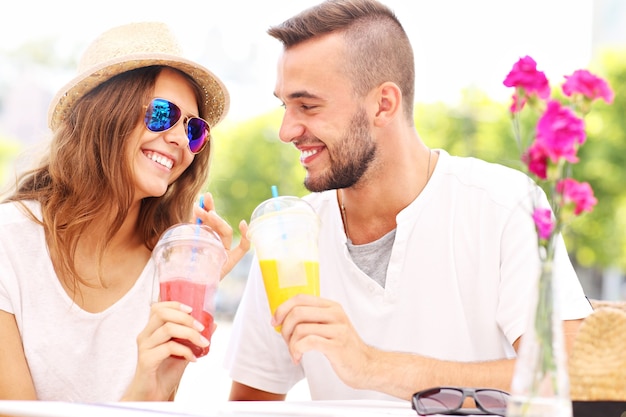 un couple heureux buvant des smoothies dans un café extérieur