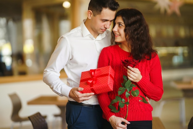 Couple heureux avec cadeau étreignant Boîte cadeau rouge dans les mains d'un couple amoureux Saint Valentin