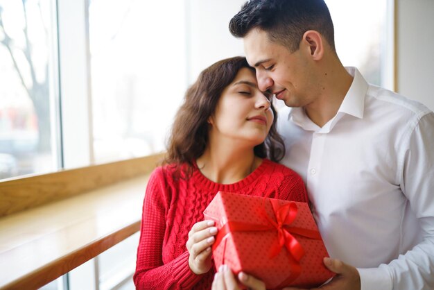 Couple heureux avec cadeau étreignant Boîte-cadeau rouge dans les mains d'un couple amoureux Saint Valentin