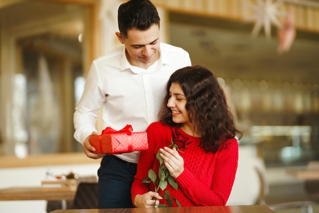 Couple heureux avec cadeau étreignant Boîte-cadeau rouge dans les mains d'un couple amoureux Saint Valentin