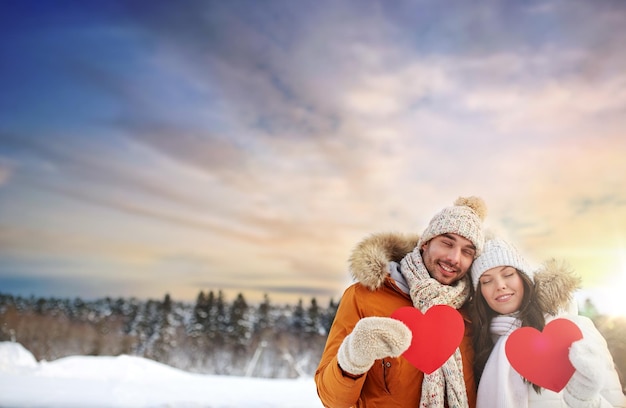 couple heureux avec des cœurs rouges sur la nature hivernale