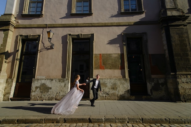 Couple heureux courir ensemble dans la rue en hiver