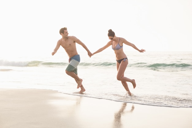 Couple heureux en cours d'exécution sur la plage