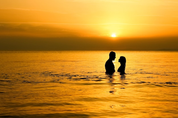 Un couple heureux dans la mer sur la silhouette de voyage nature