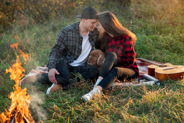 Couple heureux dans des vêtements décontractés avec leur drôle de chien assis sur la pelouse dans le parc du printemps.