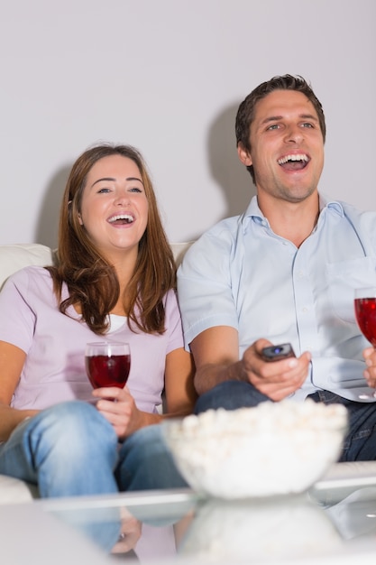 Couple heureux avec du vin et du maïs soufflé en appréciant un film à la maison