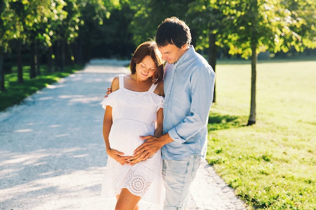 Couple heureux et enceinte étreignant dans la nature d'été Belle femme enceinte et mari à l'extérieur