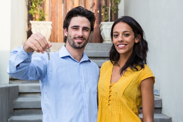 Couple heureux en face de la nouvelle maison montrant les clés