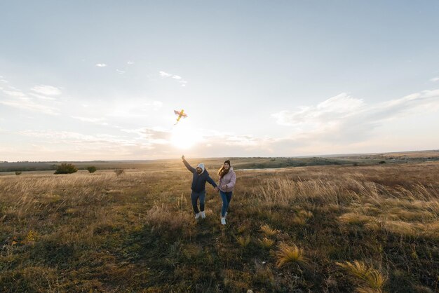 Un couple heureux fait voler un cerf-volant et passe du temps ensemble à l'extérieur dans une réserve naturelle Relations heureuses et vacances en famille Liberté et espace