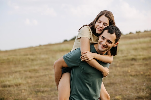 Un couple heureux d'un jeune homme et d'une jeune femme dans un champ en plein air s'embrassant