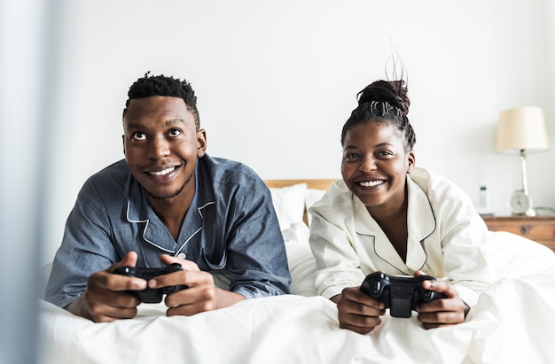 Un couple heureux jouant au jeu vidéo au lit