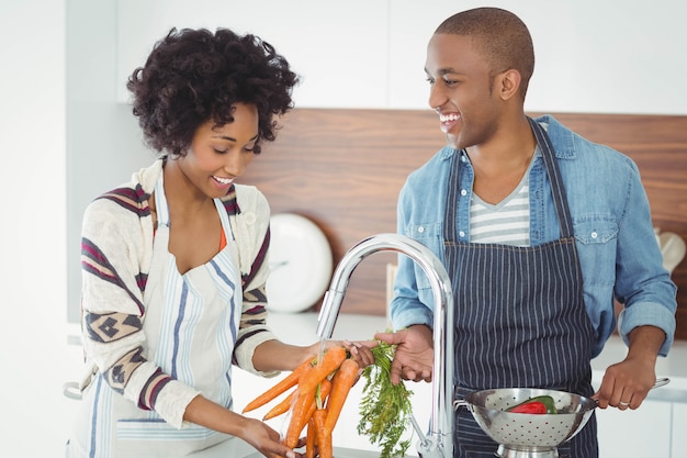 Couple heureux de laver les légumes dans la cuisine