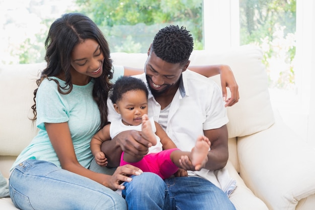 Couple heureux avec leur petite fille sur le canapé