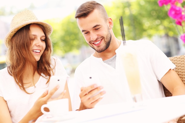 un couple heureux avec leurs smartphones dans un café