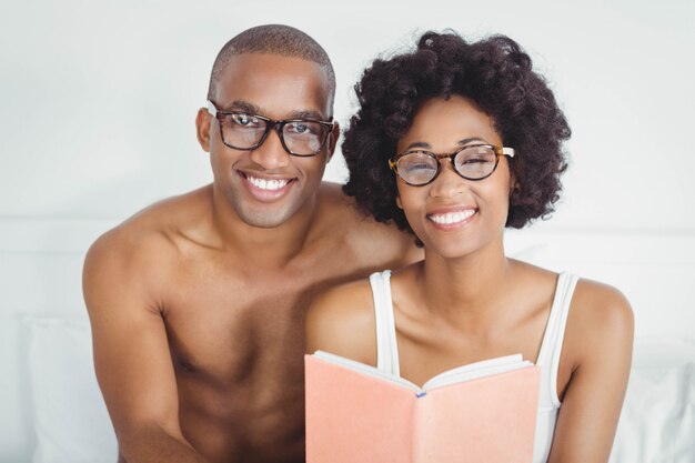 couple heureux en lisant un livre ensemble sur le lit