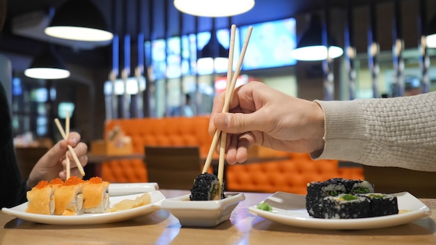 Photo couple heureux mangeant des rouleaux de sushi dans un restaurant japonais, un bar à sushis. cuisine japonaise, régime, régimes amaigrissants.