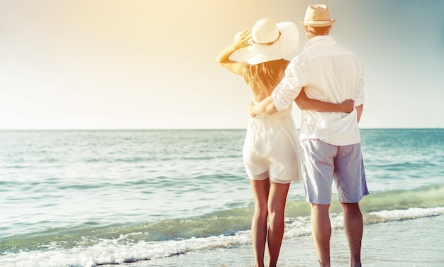 Couple heureux marchant sur la plage au bord de la mer