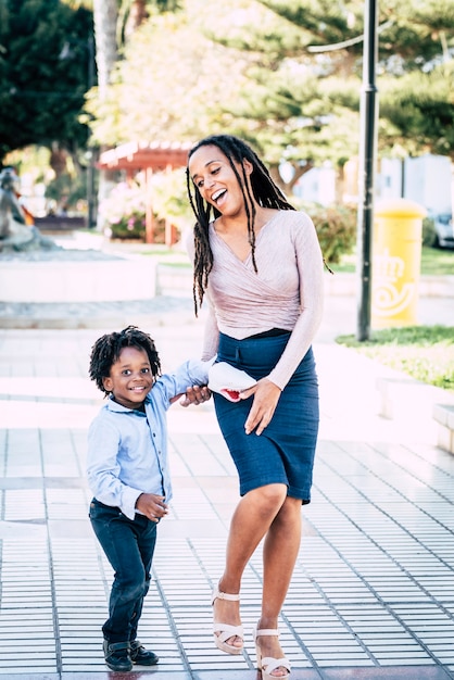 Un couple heureux mère-fils profite du parc de jeux dans la ville en s'amusant et en riant ensemble - une mère noire et ses enfants rient et sourient portrait