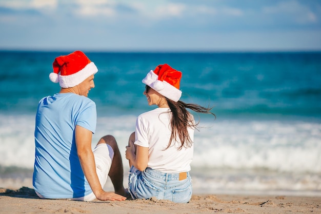 Couple heureux de Noël en chapeaux de Père Noël en vacances à la plage