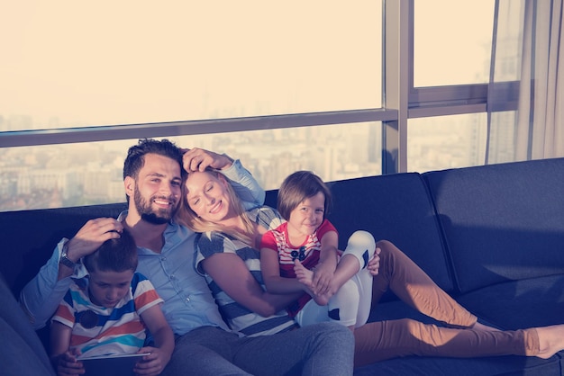 couple heureux passant du temps avec des enfants à l'aide d'un ordinateur tablette sur un canapé à la maison