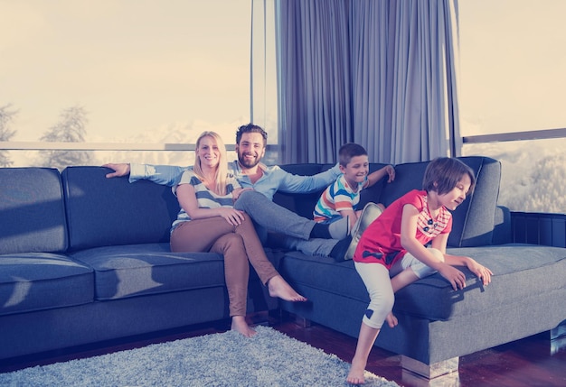 couple heureux passant du temps avec des enfants à l'aide d'un ordinateur tablette sur un canapé à la maison