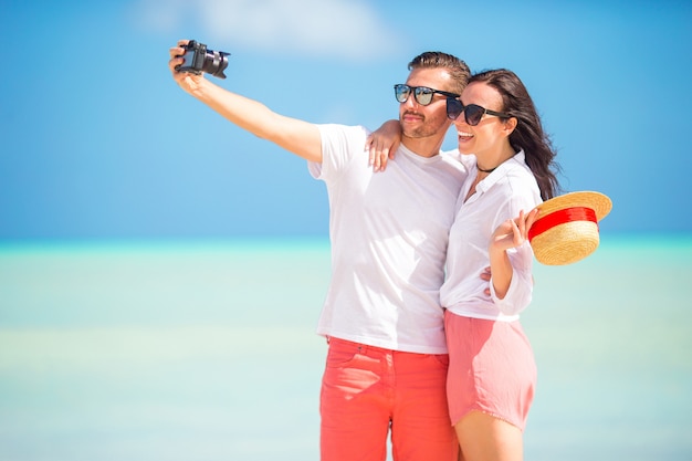 Couple heureux en prenant une photo sur la plage blanche en vacances de lune de miel