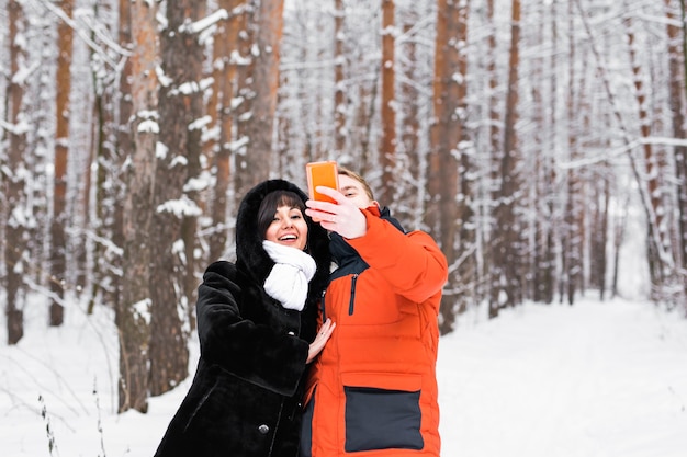 Couple heureux prenant selfie par smartphone en hiver.