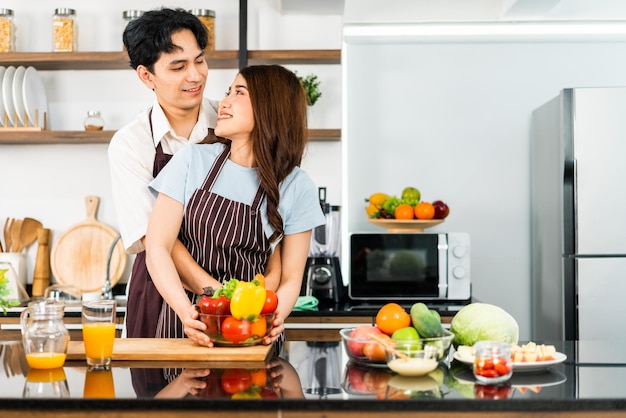 Un couple heureux prépare et cuisine une salade saine avec des légumes sur une planche à découper ensemble dans la cuisine de la maison Cuisine pour jeune couple mari et femme dans une bonne humeur et une relation saine