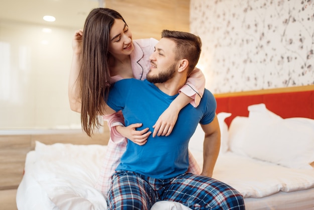 Couple heureux en pyjama relaxant au lit à la maison, bonjour. Relation harmonieuse dans la jeune famille