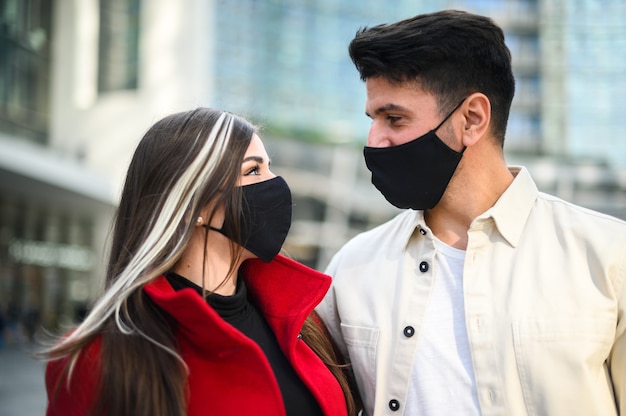 Couple heureux romantique se regardant profondément dans les yeux portant des masques contre la pandémie de coronavirus Covid 19
