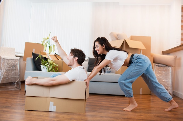 Couple heureux s'amuse avec des boîtes en carton dans une nouvelle maison au jour du déménagement