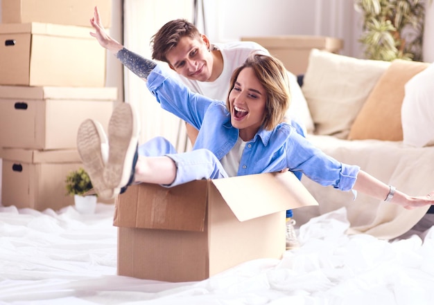 couple heureux s'amuser et monter dans des boîtes en carton à la nouvelle maison