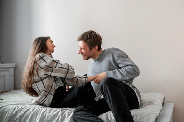 Un couple heureux s'engage dans une bataille amusante en partageant un moment d'amusement et de rire sur leur lit.