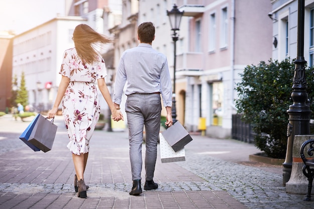 Couple heureux avec des sacs à provisions après avoir fait du shopping en ville en souriant et en s'embrassant.