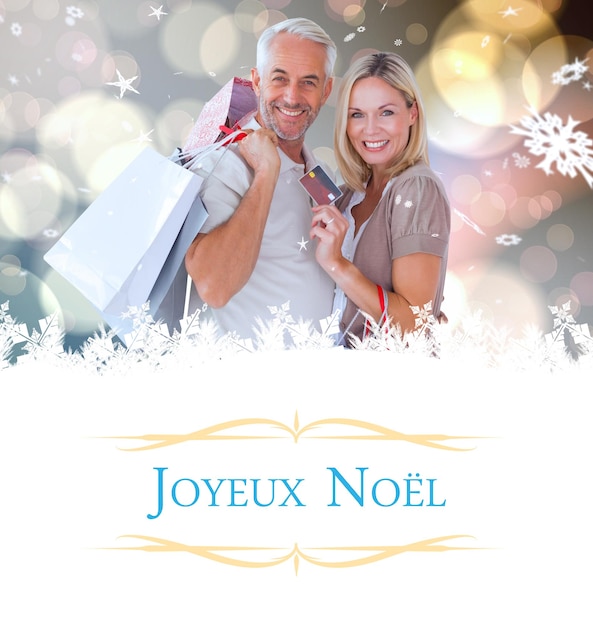 couple heureux avec des sacs à provisions et une carte de crédit contre la carte de voeux de Noël