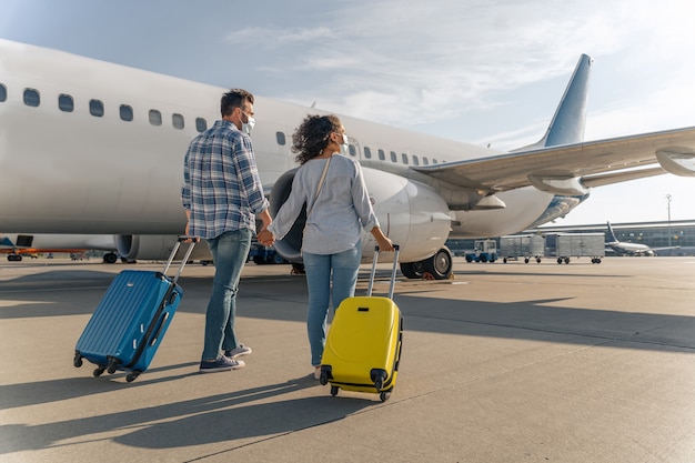 Couple heureux avec des sacs de voyage descendant l'aérodrome