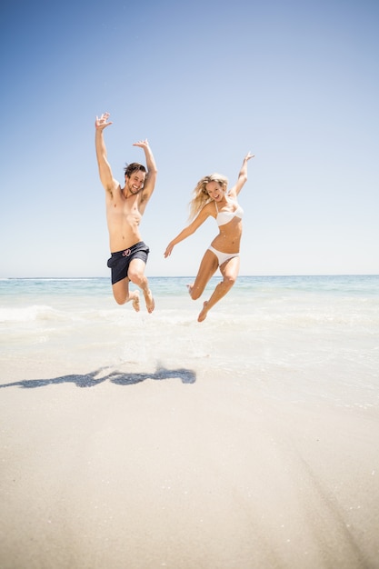 Couple heureux de sauter sur la plage